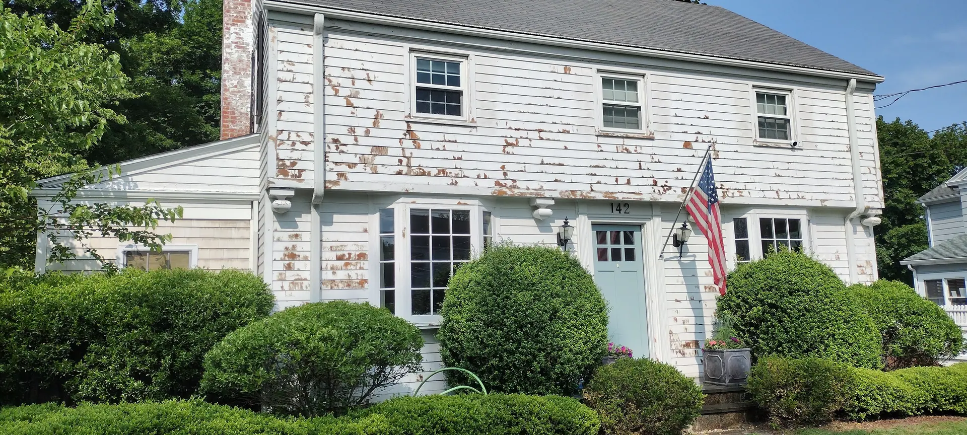 Colonial home before repainting, with peeling paint