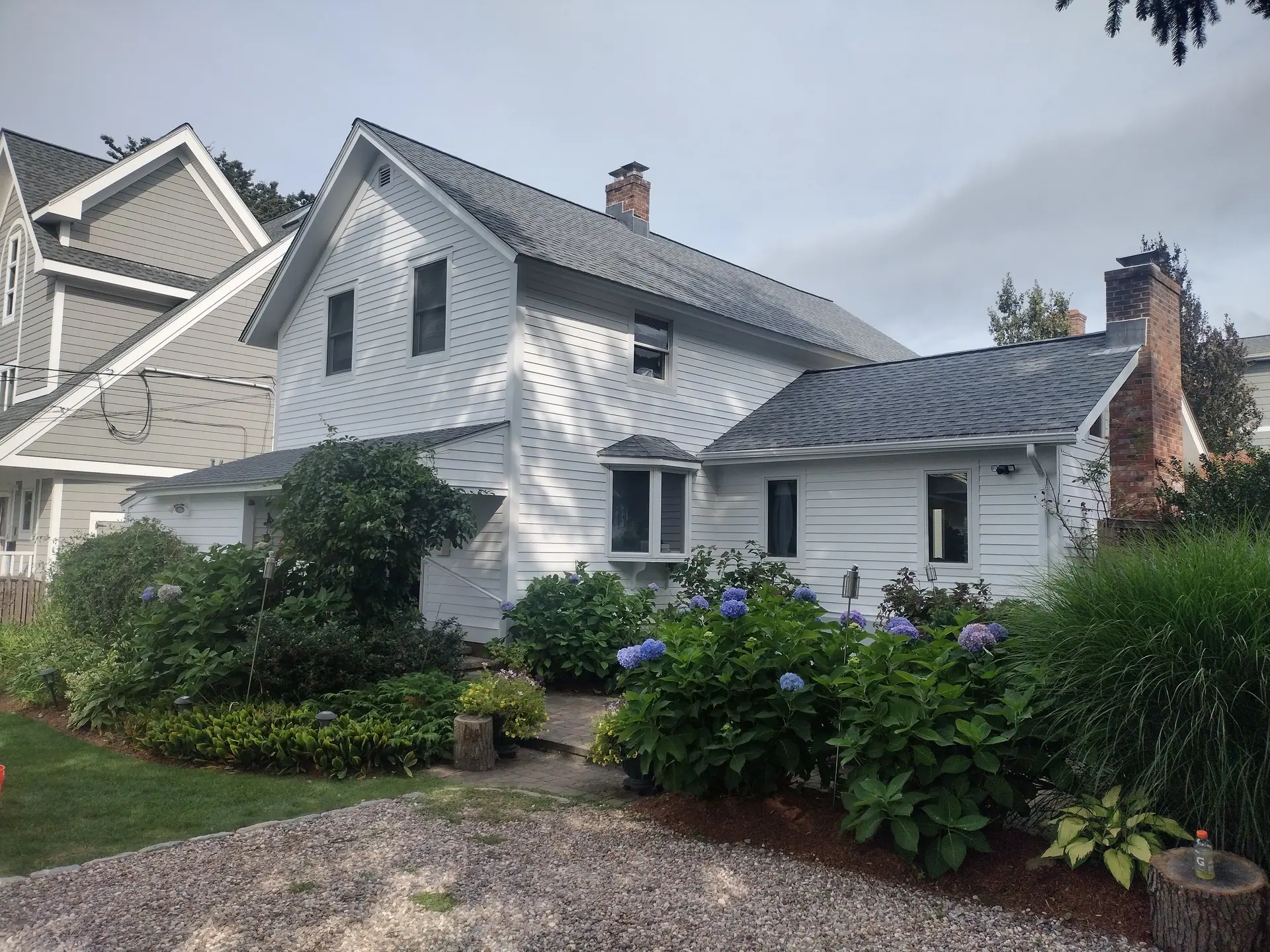 White farmhouse with fresh exterior paint, framed by blooming hydrangeas