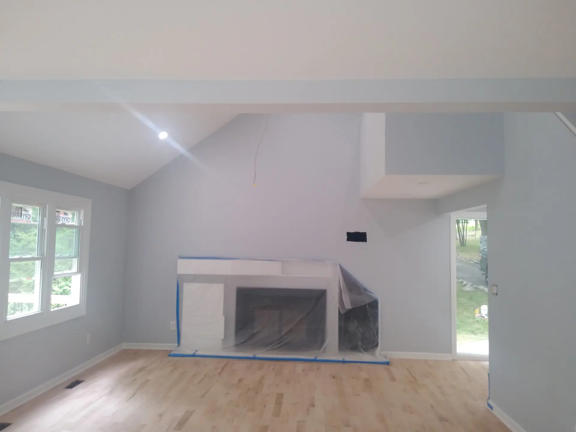 Living room mid-renovation with new hardwood floor and fireplace surround