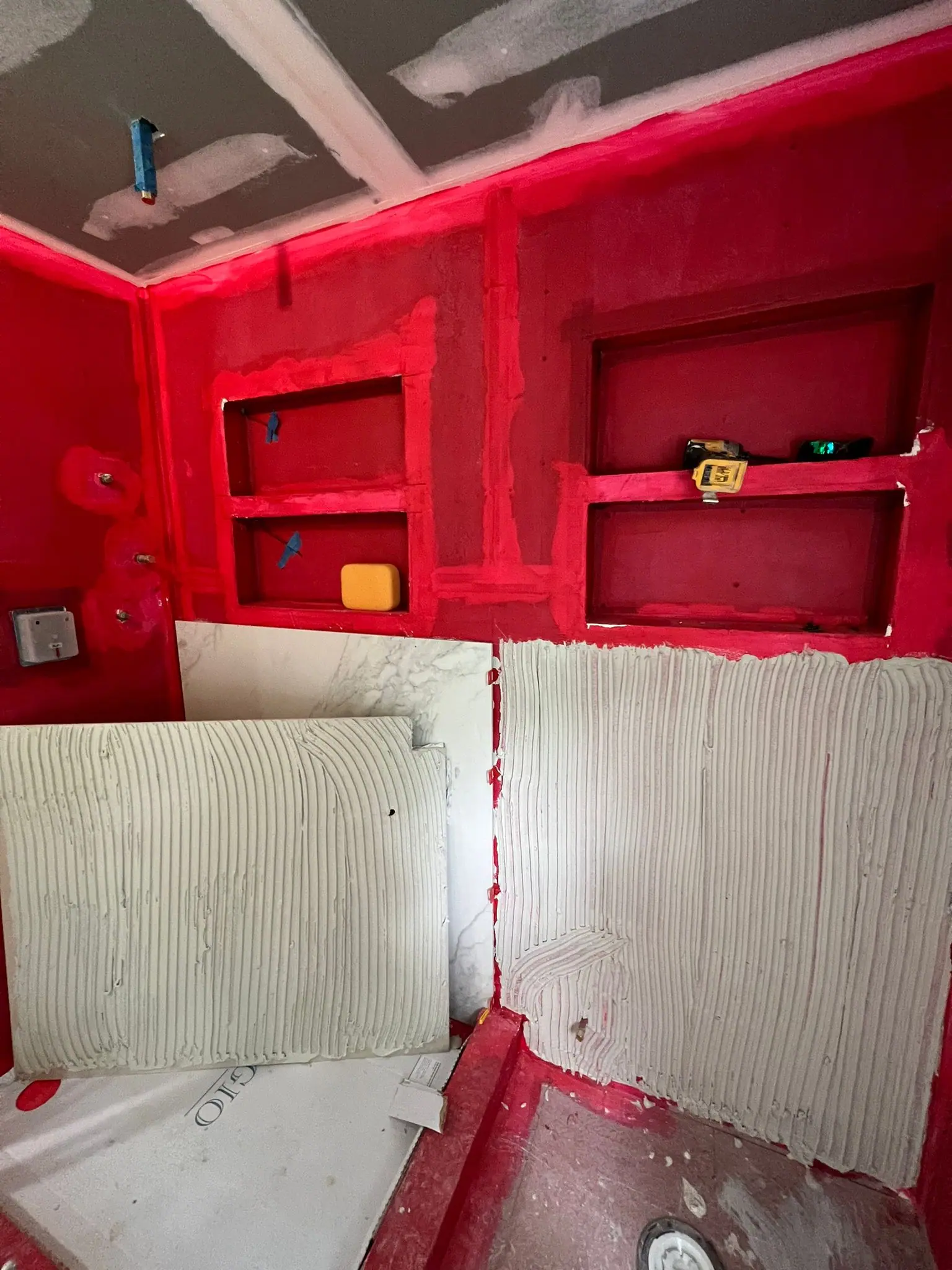 Shower walls in red waterproofing membrane with framed niches